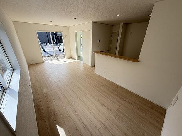 大きな窓から光が差し込むリビングです。明るいフローリングが開放感を演出しています。無駄のないすっきりとした空間が特徴です。キッチンとのつながりも便利な設計になっています。