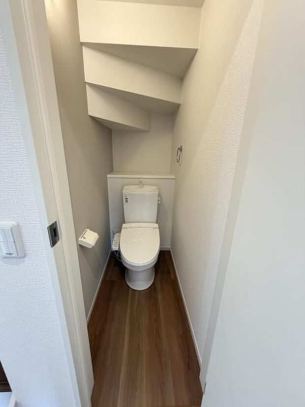 空間を有効活用したトイレでシンプルな内装が印象的です。コンパクトながらも使いやすさに配慮されています。木目調の床が落ち着いた雰囲気を演出します。