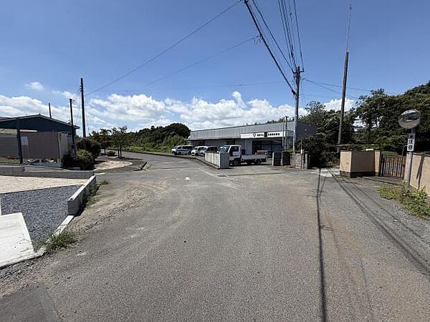 前面道路は幅が広く車の出入りがしやすい造りとなっています。アスファルト舗装されており周辺もすっきりとした印象です。周囲に建物や緑があり開放感があります。交通量も比較的落ち着いています。