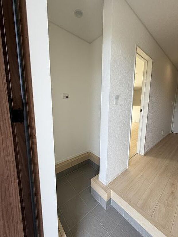 明るい色合いで仕上げられた玄関はすっきりとした印象を与えます。玄関まわりのスペースに余裕があるため使い勝手の良さもポイントです。段差部分のデザインが空間にアクセントを加えています。