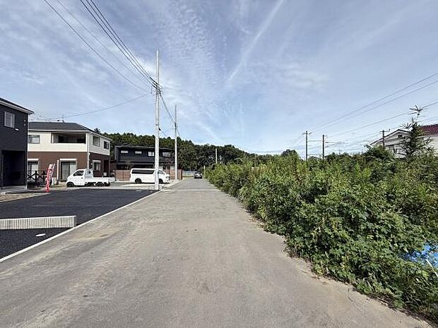 前面道路が広々としており車の出入りがしやすい現地写真です。周囲には新しい住宅が並びすっきりとした印象です。見晴らしもよく空が広く感じられる場所です。近隣に緑が多い点もポイントです。