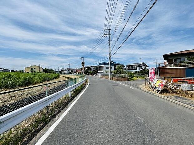 前面道路は舗装されており見通しの良い直線が広がっています。道路幅にもゆとりがあり自動車の通行も快適です。周辺には住宅や緑地が見られ落ち着いた環境が感じられます。電柱やフェンスも整然と配置されています。