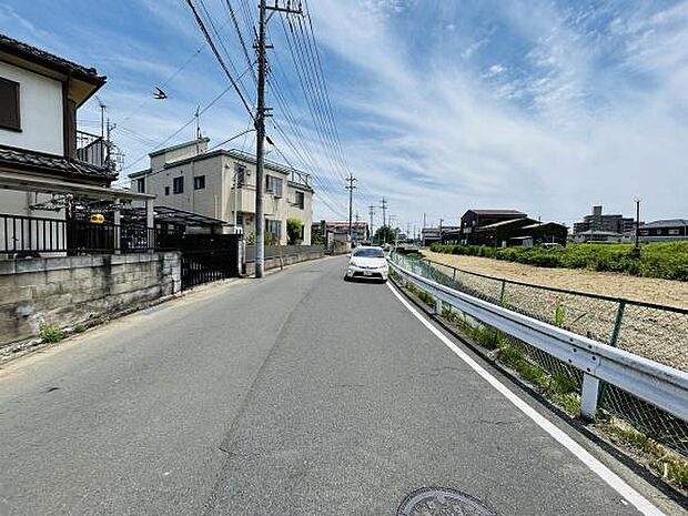 前面道路は幅員が広めで車の通行もスムーズに行えます。周囲は住宅や畑が広がるため開放感のある環境です。電線やポールも整然と配置されており整った街並みが伺えます。舗装された道路で歩きやすさも感じられます。