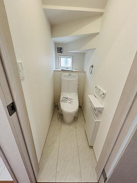手洗い付きのトイレが設置されておりコンパクトながらも空間を有効に活用しています。小窓から自然光が入り換気にも配慮されています。壁面にはペーパーホルダーと収納スペースが確保されています。