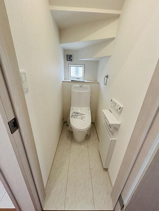 手洗い付きのトイレが設置されておりコンパクトながらも空間を有効に活用しています。小窓から自然光が入り換気にも配慮されています。壁面にはペーパーホルダーと収納スペースが確保されています。