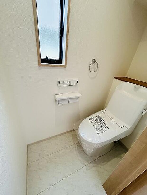 窓からの自然光が差し込む明るい印象のトイレです。シンプルで清潔感のある空間になっています。使いやすい設計でお手入れも簡単にできます。収納スペースも確保されています。