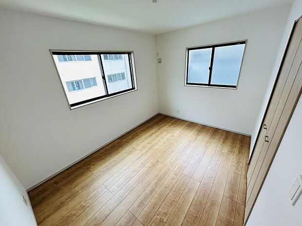 洋室は二面採光で明るさをしっかり確保しています。シンプルな内装が家具のレイアウトをしやすく落ち着いた雰囲気を持っています。木目調のフローリングが空間をすっきりと見せてくれます。