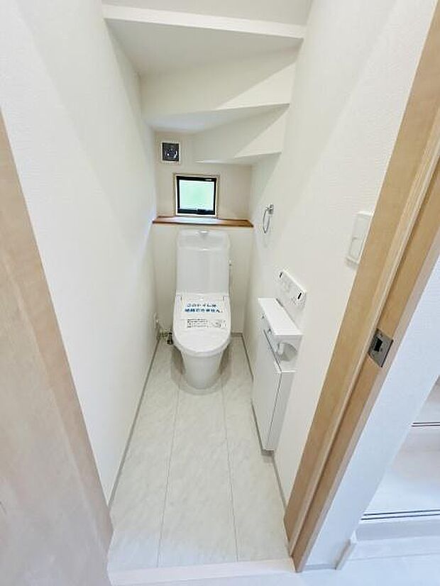落ち着いた空間に設計されたトイレです。小窓があることで明るさを確保しています。独立した手洗いスペースも配置されています。シンプルな白を基調とした内装です。清掃しやすいフロアで日々のお手入れも快適です。