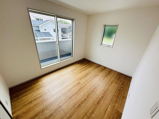 大きな窓から光が差し込む明るい洋室です。シンプルな内装で使いやすい空間です。フローリングが温かみを感じさせます。通風も良好な設計です。すっきりとした印象の洋室となっています。