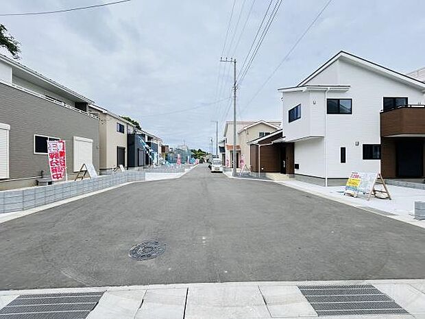 前面道路が広くすっきりとした印象です。周辺の住宅も新しく整った街並みが広がります。見通しの良い環境が特徴的です。電柱や配線も整理されており清潔感のある現地写真です。