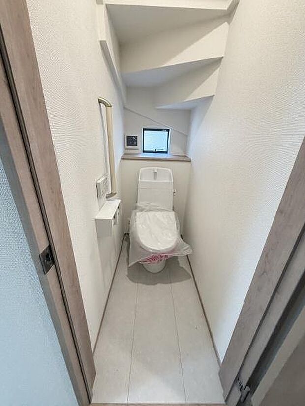 コンパクトな設計で空間を有効活用したトイレです。小窓が付いており外からの光を取り入れやすい仕様です。清潔感のあるシンプルなデザインが印象的です。ペーパーホルダーやミラーなど必要な設備が揃っています。