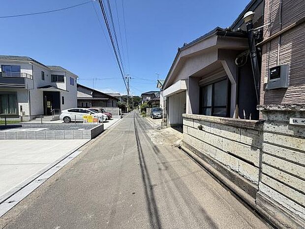 前面道路は舗装されており車の通行がしやすい環境です。周囲には住宅が立ち並び落ち着いた雰囲気が広がっています。視界が開けているため日当たりにも期待できます。近隣には駐車スペースも確保されています。