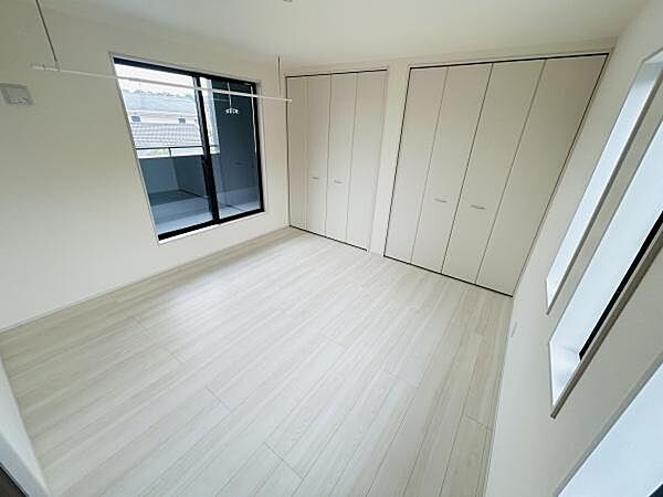明るい室内が特徴の寝室です。大きな窓から自然光が入り部屋全体が開放的に感じられます。収納スペースも豊富に確保されています。窓際にはバルコニーへの出入りも可能です。清潔感のあるフローリングが印象的です。