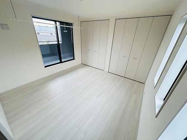 明るい室内が特徴の寝室です。大きな窓から自然光が入り部屋全体が開放的に感じられます。収納スペースも豊富に確保されています。窓際にはバルコニーへの出入りも可能です。清潔感のあるフローリングが印象的です。