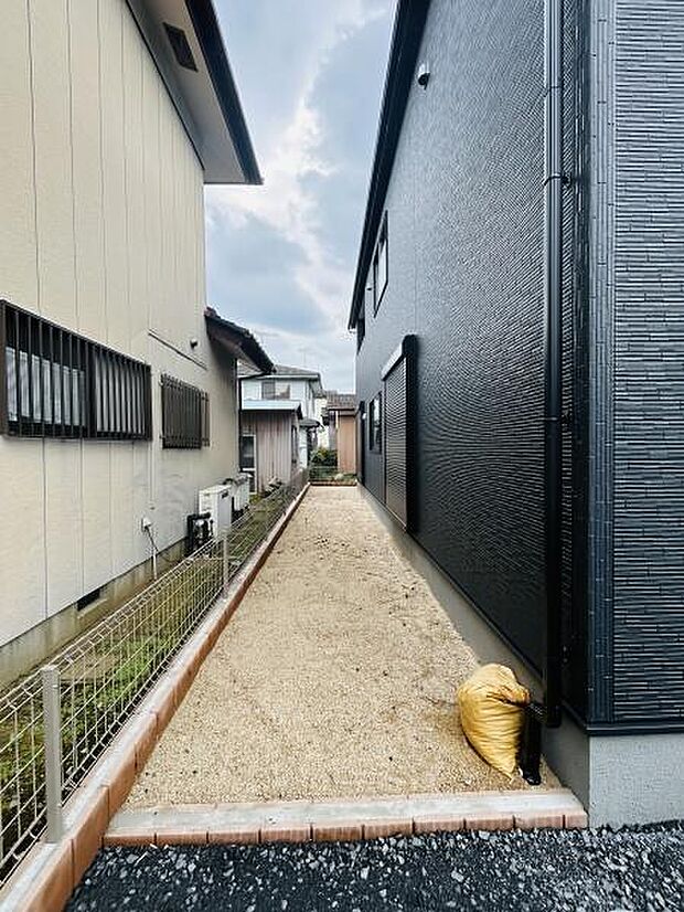 シンプルな砂利敷きで管理がしやすい庭です。隣家との間にしっかりとしたフェンスがあり安心感があります。建物側の外壁とコントラストが特徴的な空間です。奥まで一直線に広がる庭のスペースが確保されています。