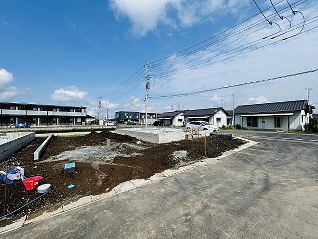 周辺には新しい住宅が立ち並び開放感のある街並みが広がります。角地に位置しており車の出入りがしやすい設計です。前面道路も広々としており建築工事も順調に進んでいます。青空の下で明るい雰囲気を感じられます。
