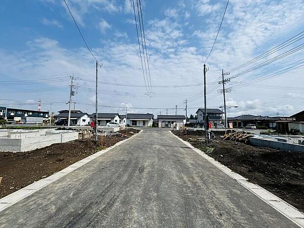 現地前面道路は幅が広く車の出入りもスムーズに行えます。周辺には新しい住宅が建ち並び整備された区画が印象的です。晴天の下開放感を感じられる眺めとなっています。