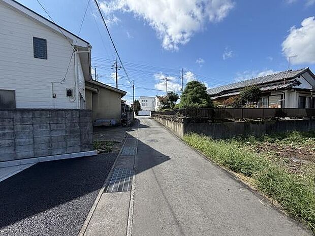 前面道路がしっかり舗装されており周辺の住宅との程よい距離感が感じられます。空が広く開けているため開放的な雰囲気です。道路沿いには植栽や住宅が並び落ち着いた環境が広がっています。