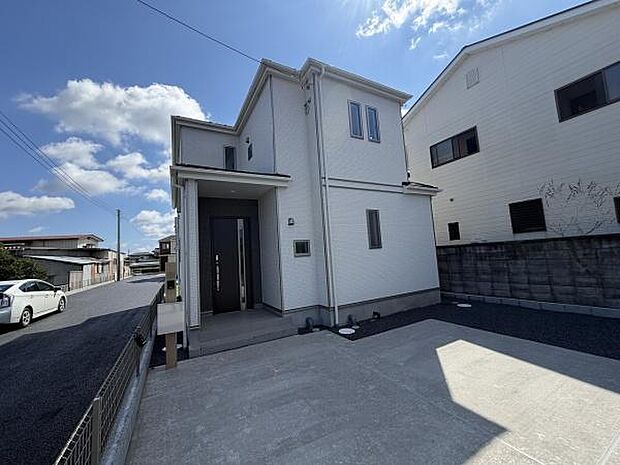 白を基調とした外観が特徴の住宅です。シンプルで落ち着いたデザインが魅力です。玄関までのアプローチもすっきりと整えられています。窓の配置がバランスよく明るい印象を演出しています。