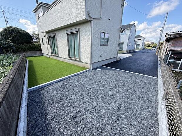 人工芝と広い駐車スペースが特徴の庭です。手入れがしやすく開放的な空間が広がっています。外観に調和したレイアウトがポイントです。日当たりも確保されています。シンプルな造りで使い勝手が良いです。