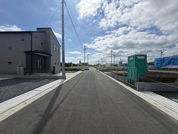 前面道路はゆったりとした幅員で車の通行も安心です。周囲には電柱や住宅が整然と配置されています。空が大きく広がっており開放的な雰囲気が感じられます。幅広い道路が住環境をサポートします。