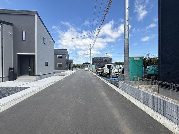 前面道路は見通しが良く車の出入りもスムーズに行えます。周囲は新しい住宅と整備された道が特徴的です。青空が広がり開放感のある街並みが印象的です。道路幅も十分に確保されています。
