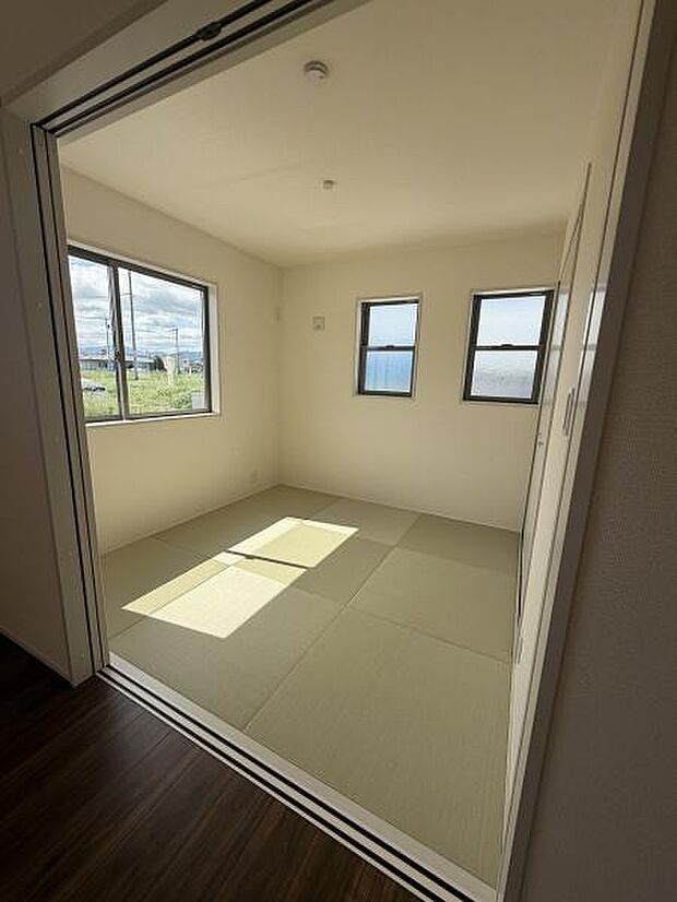 明るい光が差し込む清潔感のある和室です。大きな窓からの眺めも楽しめます。独立した空間として活用しやすい設計です。畳の質感が落ち着いた雰囲気を演出します。三面採光により日中も快適な明るさです。