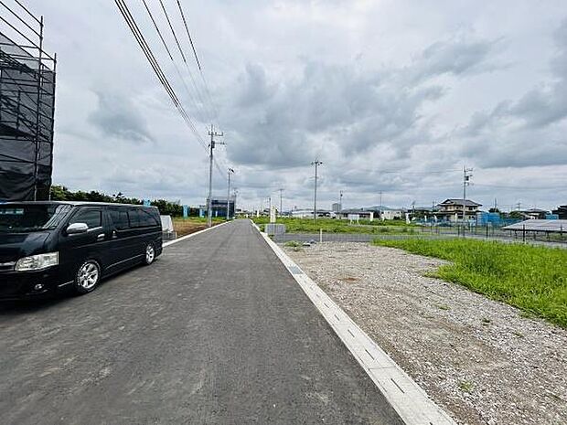広々とした前面道路が特徴的な現地写真です。車の出し入れもしやすく見通しの良い通りが印象的です。周辺は落ち着いた雰囲気で建築条件付きの新規区画も確認できます。整った道路環境で快適な生活が期待できます。