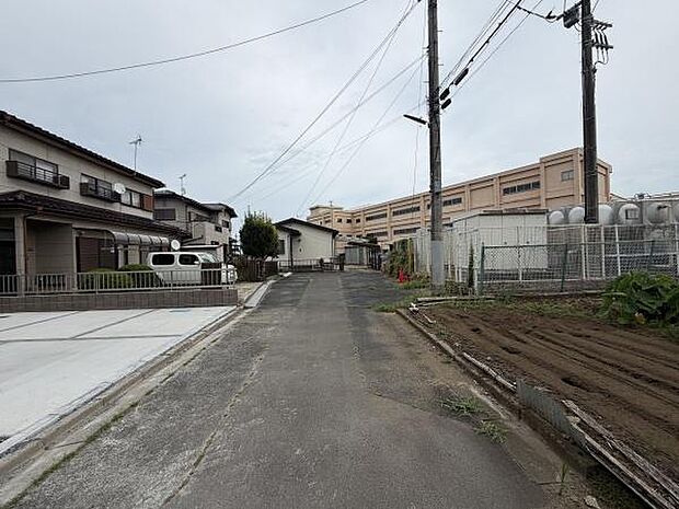 現地周辺は落ち着いた雰囲気の住宅街が広がっています。前面道路は広めで車の出入りもスムーズです。周囲には戸建住宅や施設があり生活環境が整っています。電柱やフェンスなども整備されています。