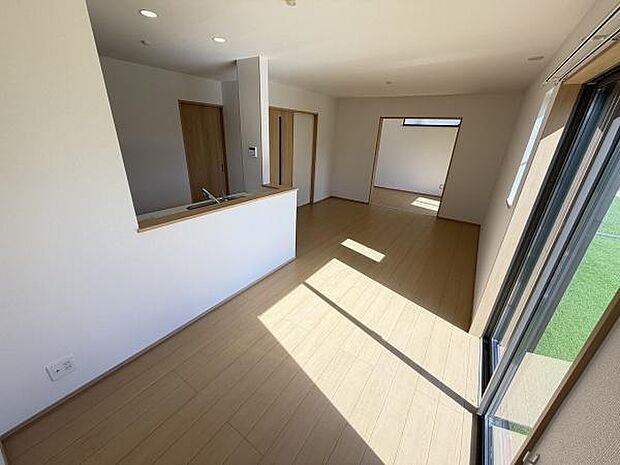 リビングの大きな窓から光が差し込み明るく開放感があります。床と建具の色合いが統一されてすっきりとした印象です。キッチンとリビングがつながっており生活動線もスムーズに設計されています。