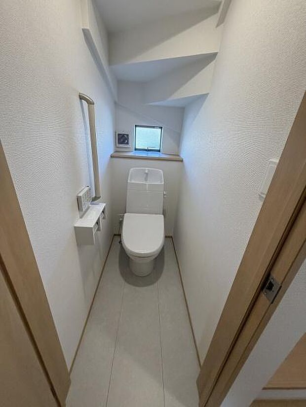小窓が設置されており換気や採光に配慮されたトイレです。手洗い一体型の便器が採用されています。ホワイトを基調とした内装で清潔感があります。段差の少ないフラットな床面が特徴です。