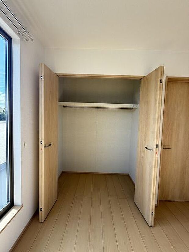 扉が大きく開く収納で荷物の出し入れがしやすい設計です。採光性の高い窓も近く明るい空間が確保されています。ハンガーパイプと上部棚付きで効率よく整理が可能です。木目調ドアが室内に調和しています。