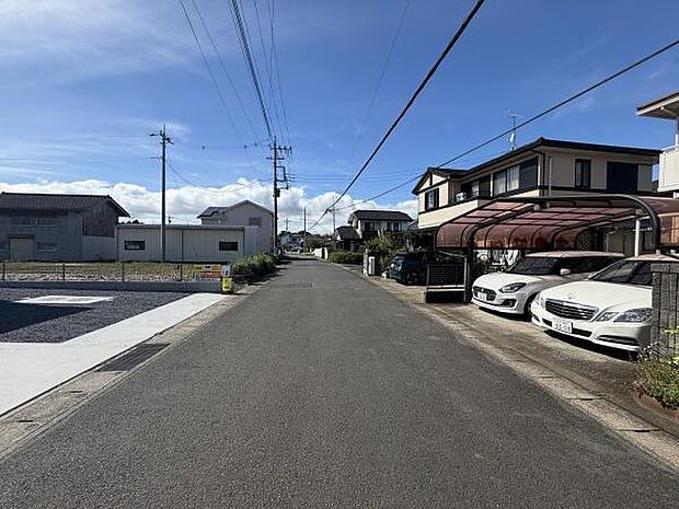周囲には住宅が並び落ち着いた雰囲気が伝わる現地写真です。前面道路はゆとりがあり車の出し入れもスムーズに行えそうです。道路沿いには電柱や配線も整備されておりきちんとした街並みが印象的です。