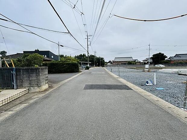 前面道路が広く車の通行にも余裕があります。周囲には住宅や敷地が点在しており落ち着いた印象です。道路の舗装状態も良好ですっきりとした景観です。電柱や配線も整理されていて視界を遮りにくいです。