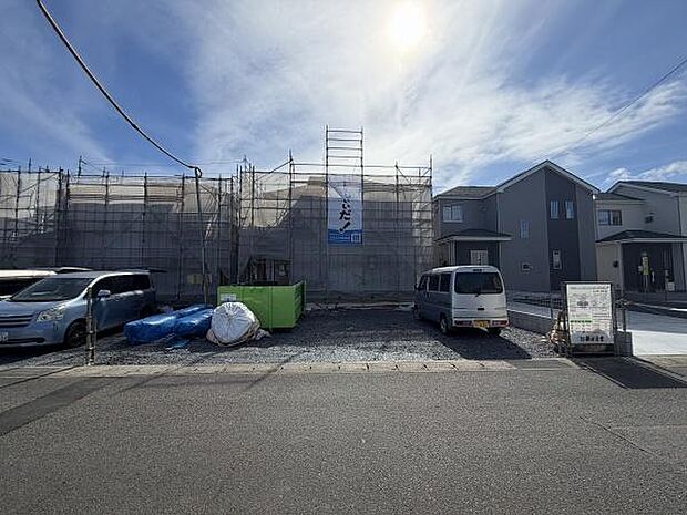 日当たりの良い前面道路と工事中の建物が特徴です。駐車スペースも確保されていて暮らしやすさが感じられます。周囲の住宅と調和した外観が印象的です。青空が広がった環境もポイントです。