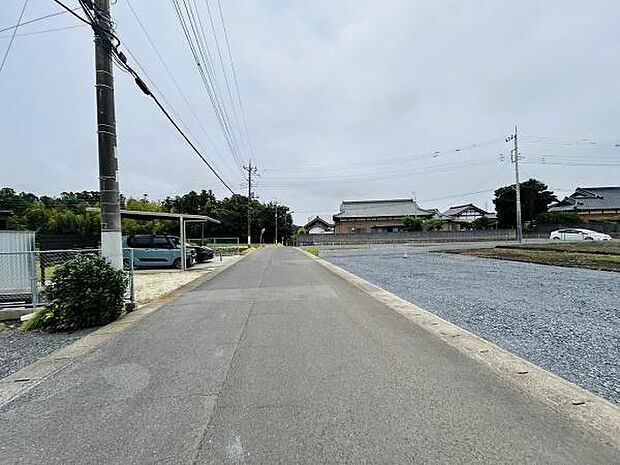 前面道路は広々としており車の出し入れもスムーズに行えます。周辺は閑静な住宅街で落ち着いた環境です。現地写真からも開放感を感じられます。電柱や舗装の様子も確認できます。駐車スペースもゆとりがあります。