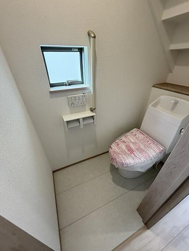 窓が設けられているため換気しやすいトイレです。手すりが設置されていて安心感があります。壁面収納スペースがあるので小物整理がしやすいです。タンク一体型トイレで空間がすっきりしています。