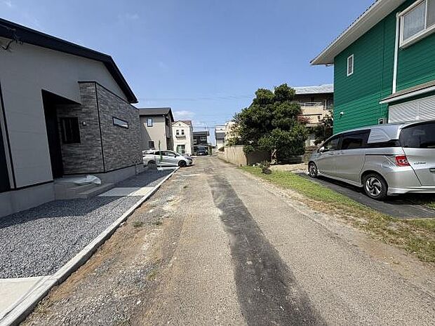 前面道路を含む現地写真です。周囲には落ち着いた住宅が並び道路幅もゆったりとしています。陽当たりも良好で開放感のある雰囲気が感じられます。車の出し入れもスムーズにできそうな現地環境です。