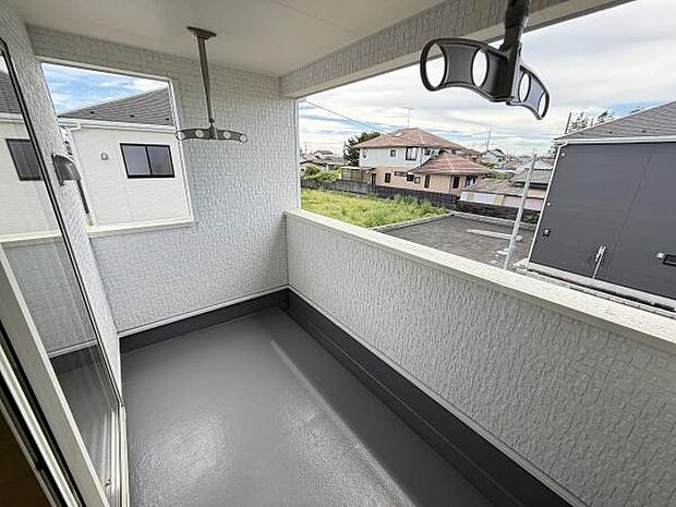 広々としたスペースが確保されたバルコニーです。屋根付きのため天候に左右されにくく快適に利用できます。周囲には建物がありながらも視界が広がる設計です。物干し金具も備わっており便利です。