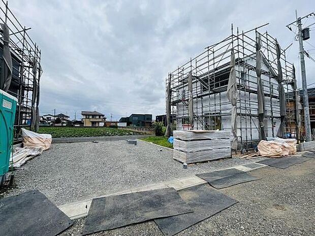 建築中の現場で広々とした敷地が印象的です。周囲には住宅や緑地が見え開放感があります。足元は整備されており資材もきちんと管理されています。落ち着いた住宅街の雰囲気が感じられます。