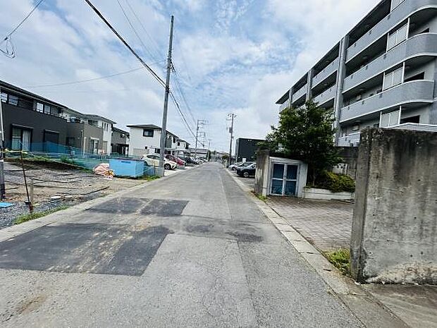 落ち着いた雰囲気の前面道路で周囲には住宅やマンションが立ち並んでいます。道路幅も確保されており車の移動も快適です。周辺の整理された街並みが印象的です。現地の様子が分かりやすい一枚となっています。