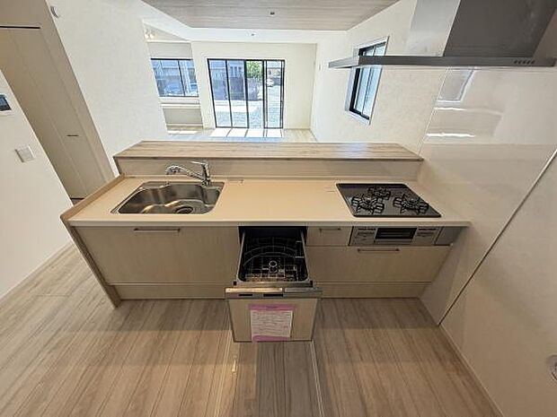 シンプルなデザインのキッチンが魅力的です。収納スペースも充実しており使いやすさが感じられます。食洗機が設置されていて日々の家事をサポートします。三口コンロで調理がスムーズに行えます。
