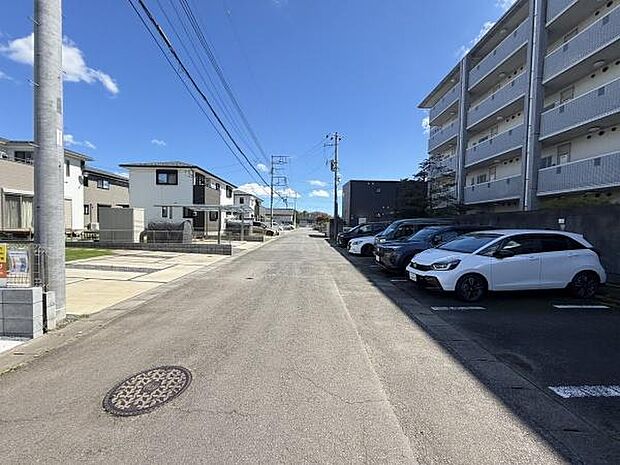前面道路は舗装されておりすっきりとした景観が広がっています。道幅にもゆとりが感じられ車の出入りも安心です。周辺には住宅や集合住宅が立ち並び駐車スペースも確保されています。