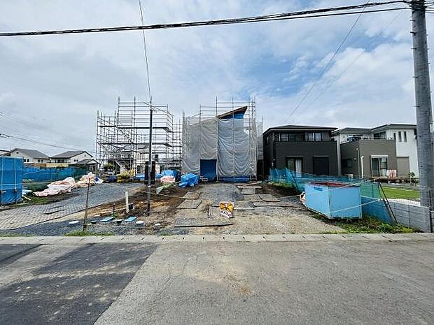 新築戸建ての建設現場の様子です。住宅街に位置し周囲も新しい建物に囲まれています。前面道路が広く車の出入りもスムーズに行えそうです。敷地もゆとりがあり複数台分の駐車スペースが確保されています。