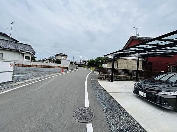 前面道路はゆるやかなカーブが特徴で車両の出入りがしやすい環境です。道幅にもゆとりがあり駐車もしやすくなっています。周囲には住宅が並び落ち着いた雰囲気が漂っています。