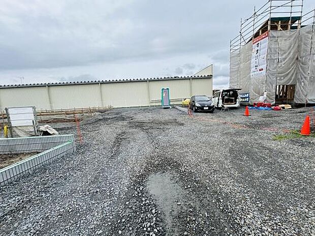 現地の様子がひと目で分かる写真です。敷地全体の広がりや道路状況が確認できます。周辺に建設中の建物や車両も映っており工事の進捗も見て取れます。敷地形状やアプローチ部分がしっかり確認できます。