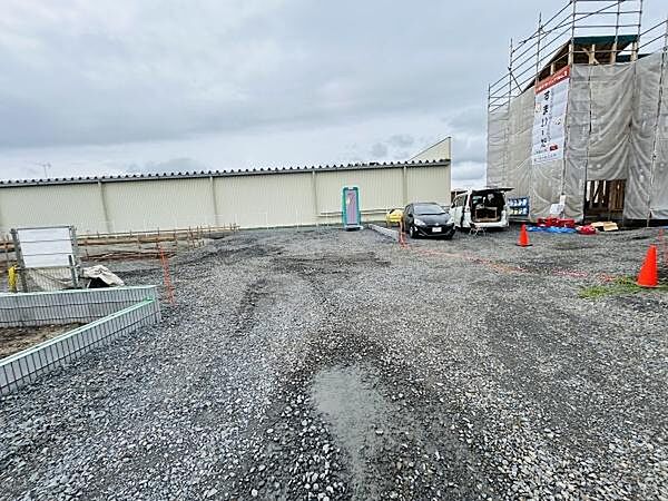 現地の様子がひと目で分かる写真です。敷地全体の広がりや道路状況が確認できます。周辺に建設中の建物や車両も映っており工事の進捗も見て取れます。敷地形状やアプローチ部分がしっかり確認できます。
