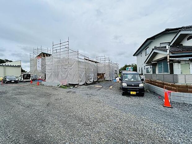 建設中の建物と広々とした敷地が特徴的です。車の駐車スペースも確保しやすい環境となっています。周囲に住宅があり落ち着いた雰囲気が感じられます。工事の進捗が視覚的に確認できる現場写真です。