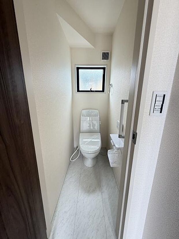 清潔感のあるシンプルなトイレ空間です。小窓が設けられており明るさと換気の確保に役立っています。白を基調とした内装で落ち着いた雰囲気です。手洗い場やペーパーホルダーも備わっています。