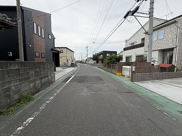 前面道路は車通りが比較的穏やかで歩道も設けられています。周辺は住宅が立ち並び整然とした印象です。広さを感じる道路幅で運転時も安心しやすい環境です。電柱や配線も整理されています。